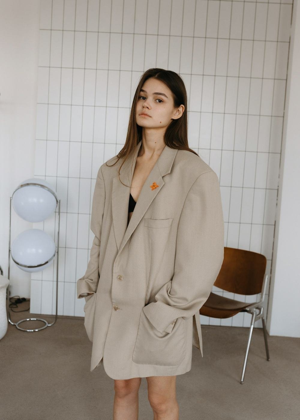 Modelo veste o Blazer Alfaiataria Linho na cor areia, com a flor laranja na lapela