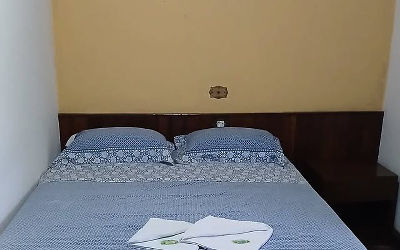 Quarto de casal com roupa de cama azul e toalhas dobradas